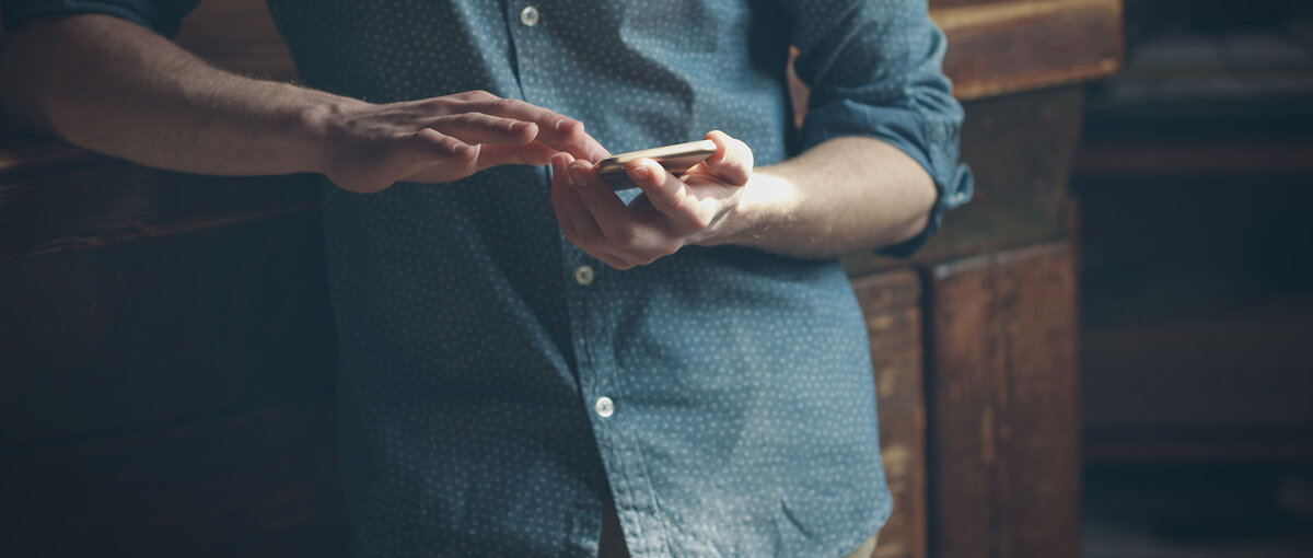 Hipster-Mann mit Smarphone lehnt an Möbel
