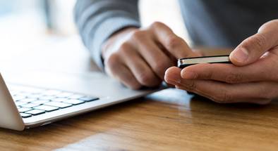 Mann mit Laptop und Smartphone in der Hand