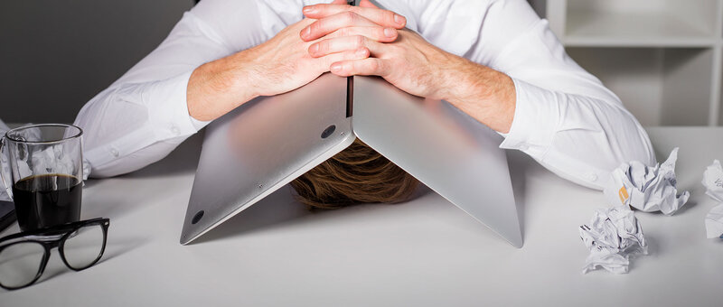 Mann versteckt unter Laptop